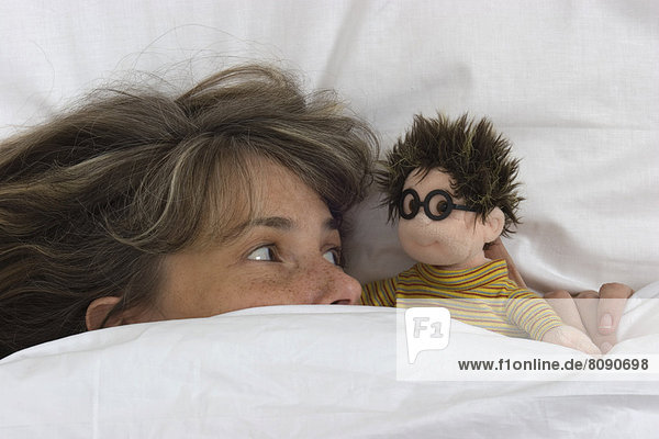 Frau mit Puppe im Bett