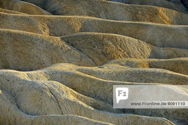 Blick von Zabriskie Point auf durch Mineralien verfärbte erodierte Gesteinsformationen  Abendlicht