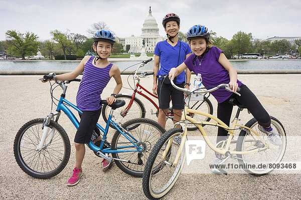 Mother and daughters riding bicycles by Capitol Building  District of Columbia  United States