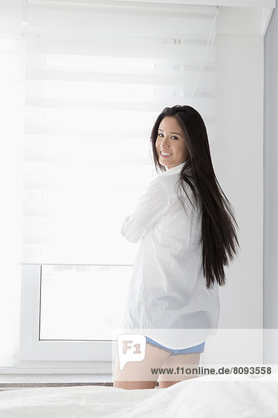 Mixed race woman smiling in bedroom