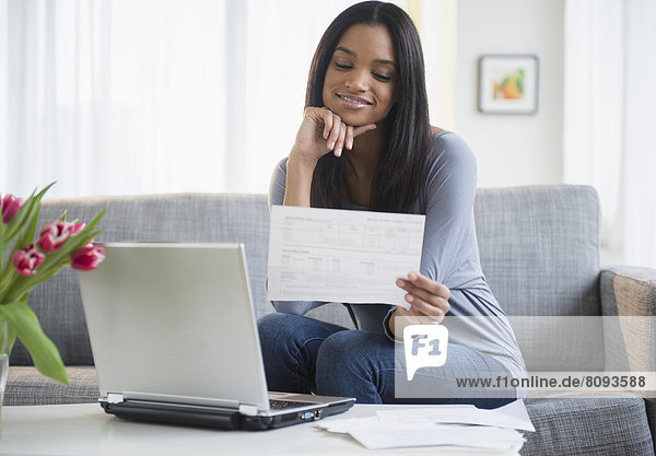 Mixed race woman paying bills with laptop