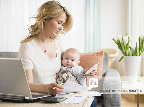 Caucasian mother with baby paying bills