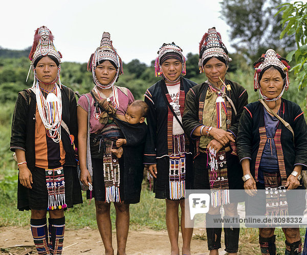 Fünf Akha Frauen in einem Bergdorf mit traditioneller Kleidung und Kopfbedeckung