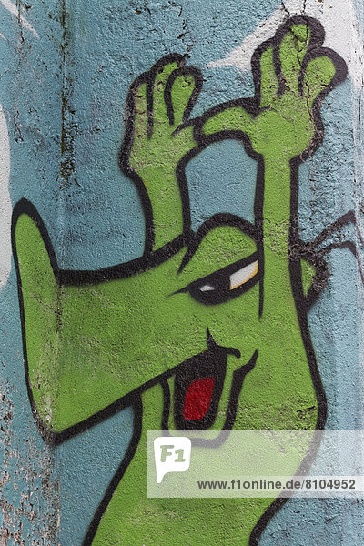 Grüne Comicfigur hält die Hände hoch  Graffito
