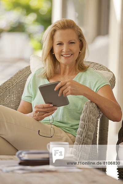 Porträt einer lächelnden Frau mit digitalem Tablett auf der Veranda