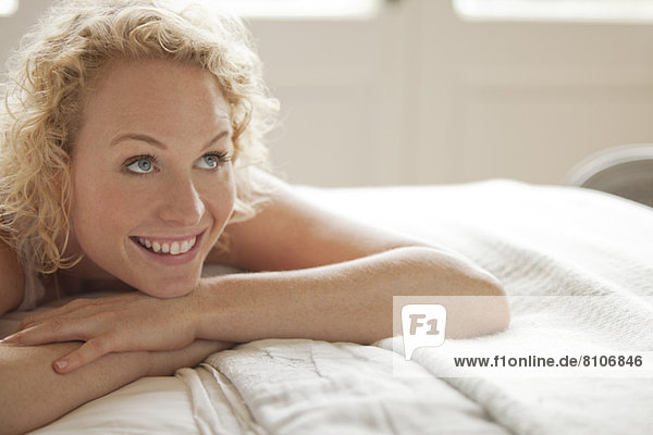 Enthusiastic woman laying in bed and looking up