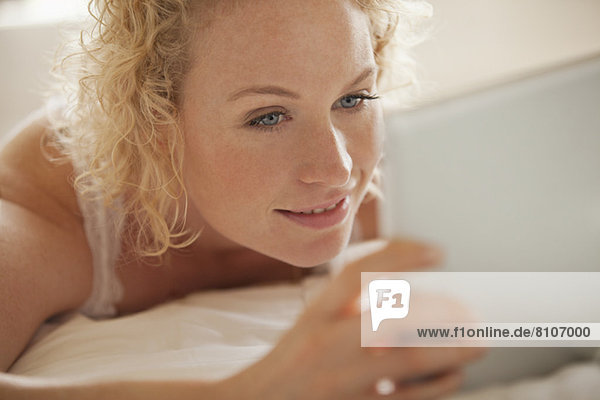 Nahaufnahme der Frau mit digitalem Tablett im Bett