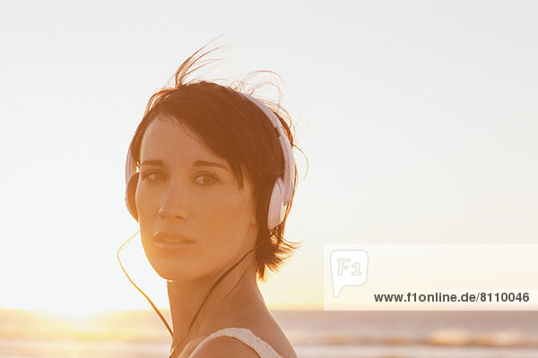 Nahaufnahme des Porträts einer selbstbewussten Frau mit Kopfhörer am Strand