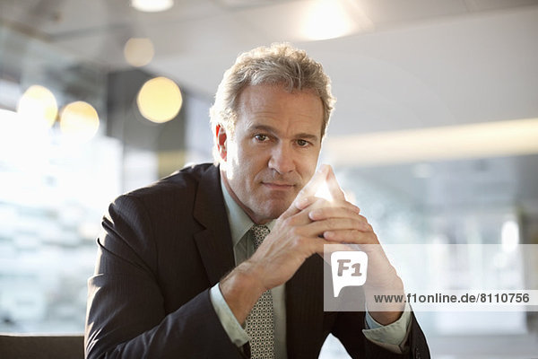 Portrait of confident businessman with hands clasped