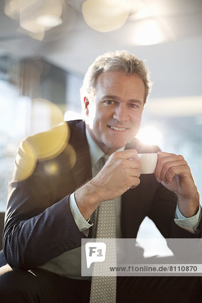 Portrait of smiling businessman drinking espresso