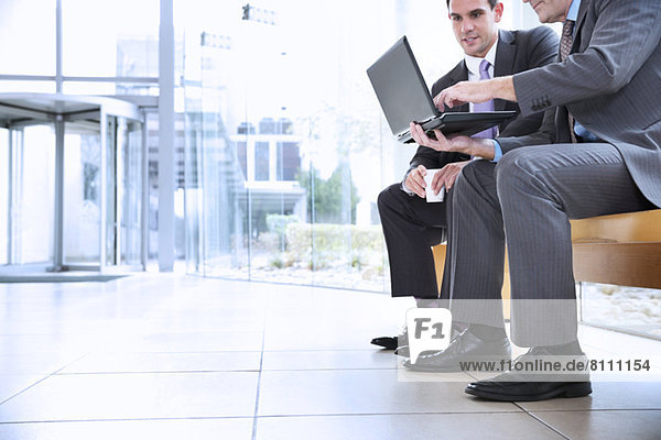 Businessmen sharing laptop in lobby