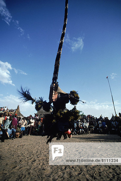 Africa Youdiou Sky Clouds Sand Costume Mask Dogon One Man Tribal Man Large Group Of Spectators Large Group Of People Dancing Standing Jumping Culture Watching Tradition Folk Dance Celebration Aggression Mid Air Tribal Culture Outdoors Day Side View Low Angle View Vertical Color Image Photography