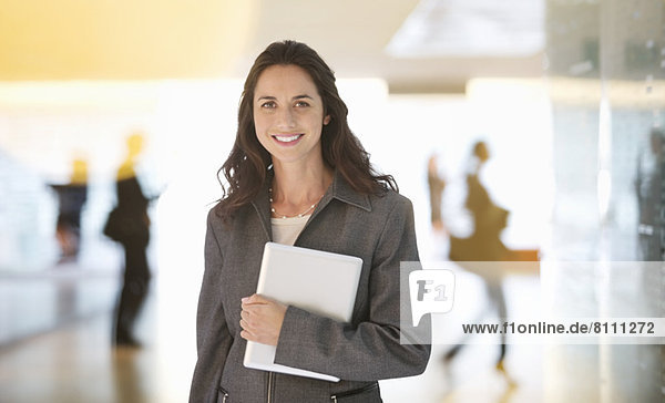 Portrait of smiling businesswoman holding digital tablet in lobby