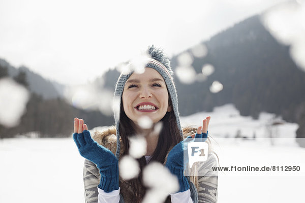 Happy woman enjoying falling snow in field