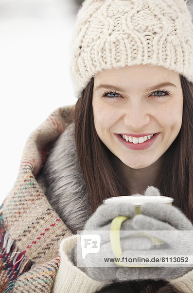 Close up portrait of woman in knit hat and gloves drinking coffee