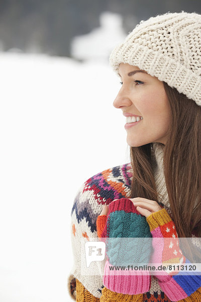 Close up of smiling woman wearing knit hat and fingerless gloves in snowy field
