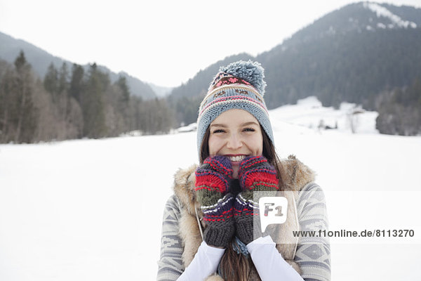 Portrait of enthusiastic woman wearing knit hat and gloves in snowy field
