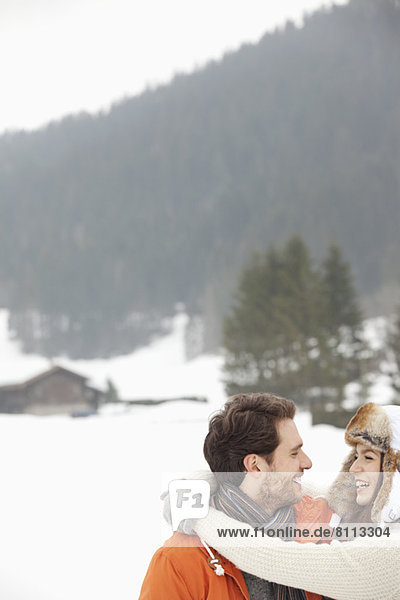 Happy couple hugging in snowy field