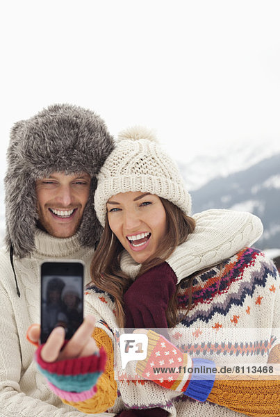 Enthusiastic couple taking self-portrait with camera phone