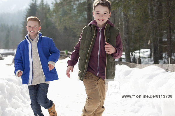 Portrait of happy boys running in snowy lane