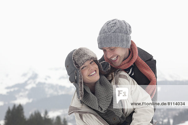 Portrait of enthusiastic couple hugging with mountains in background