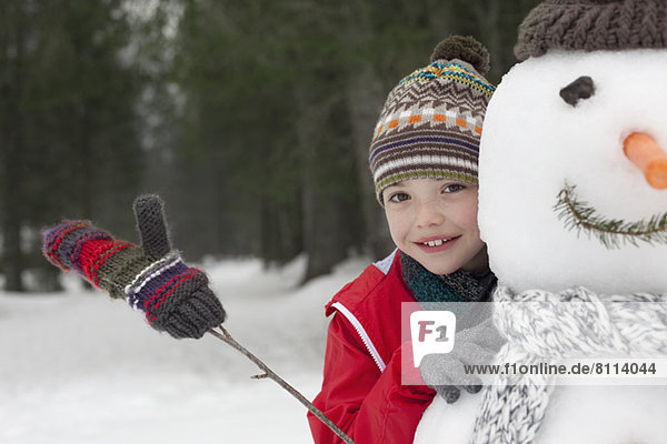 Close up of smiling boy behind snowman