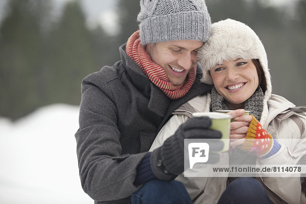 Happy couple drinking coffee in snow