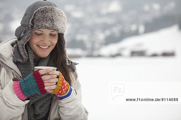 Smiling woman drinking coffee in snow