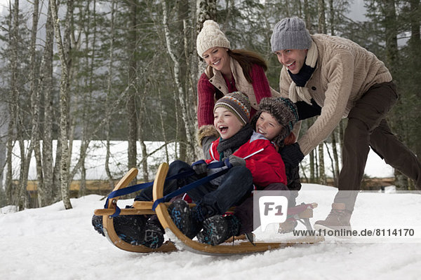 Happy family sledding in snowy woods