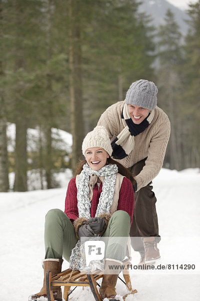 Happy couple sledding in snowy woods