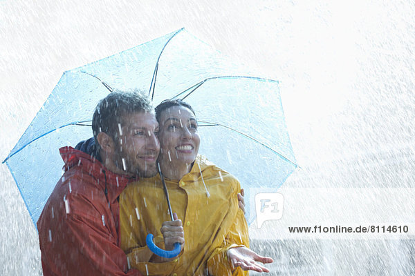 Happy couple under umbrella in rain