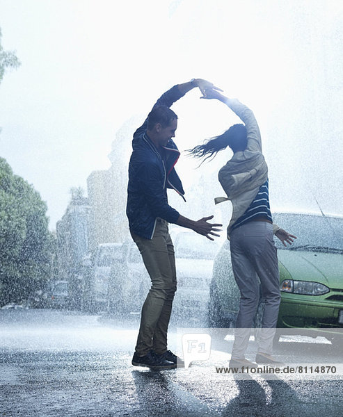 Happy couple dancing in rain