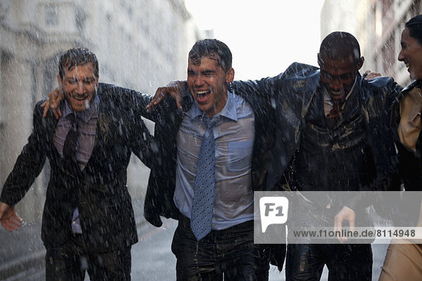 Happy businessmen walking in rainy street