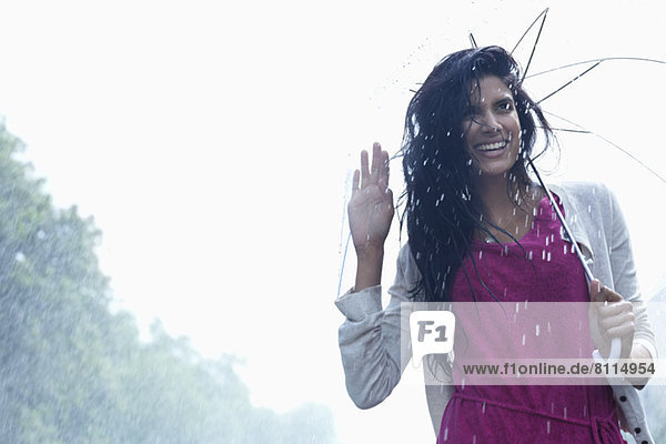 Portrait of smiling woman under umbrella in rain