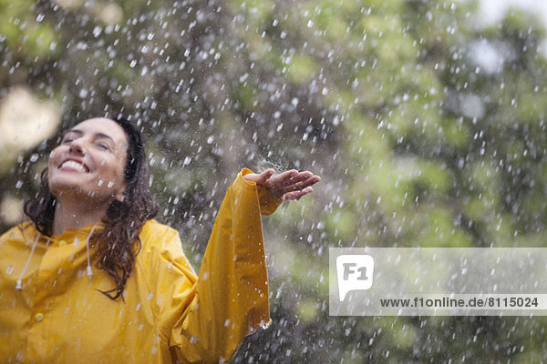 Happy woman standing with arms outstretched in rain