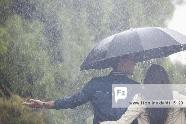 Paarlauf mit ausgestreckten Armen unter dem Regenschirm