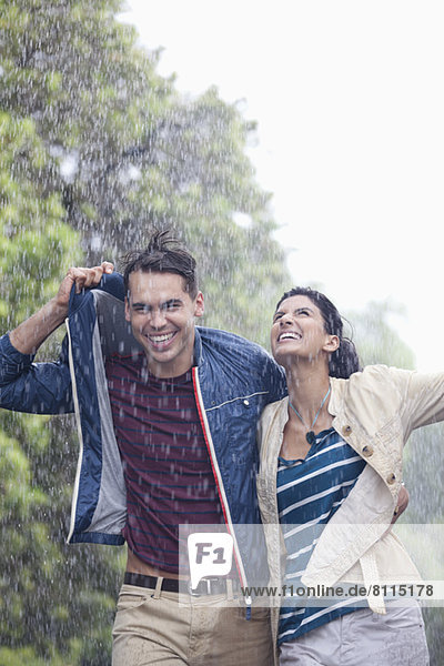 Glückliches Paar  das im Regen läuft