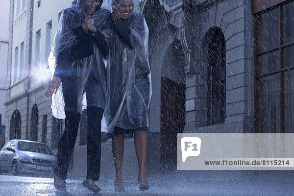 Businesswomen in ponchos walking in rainy street