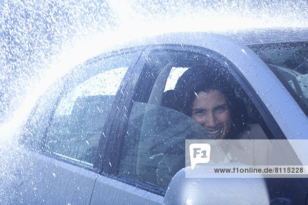 Porträt der lächelnden Geschäftsfrau im Auto bei Regen