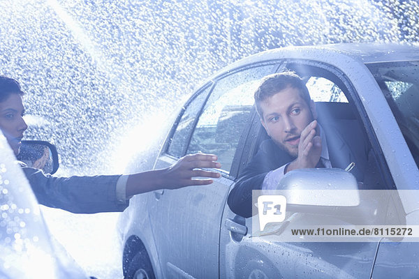 Businessman in car providing directions to woman in rain