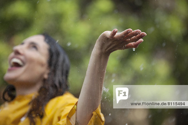 Enthusiastic woman standing with arms outstretched and head back in rain