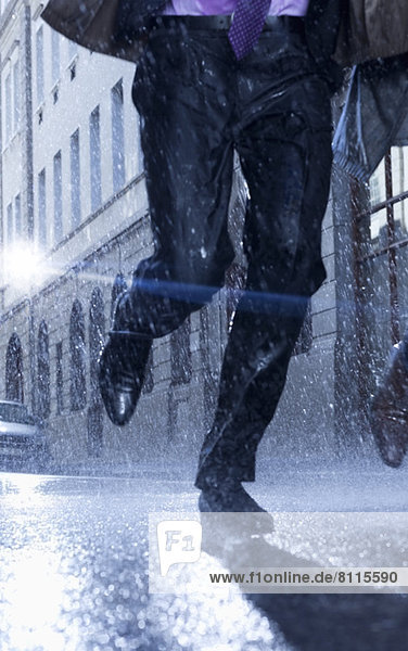 Businessman running in rainy street