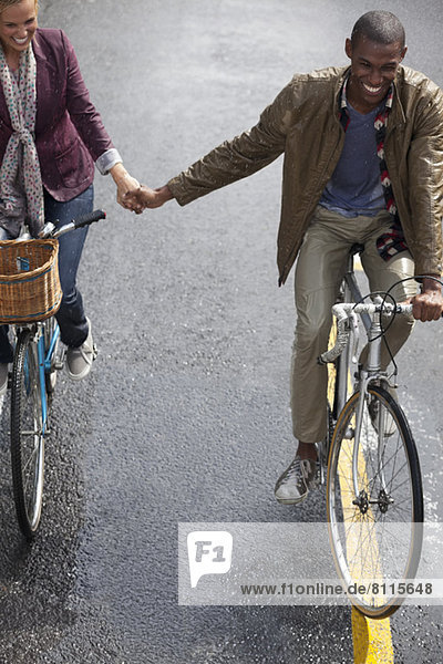 Happy couple holding hands and riding bicycles