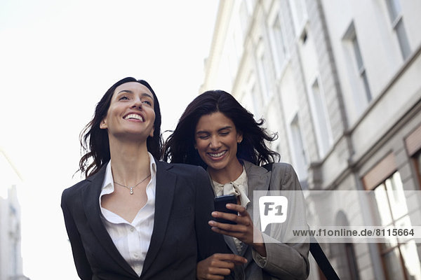 Happy businesswomen text messaging with cell phone