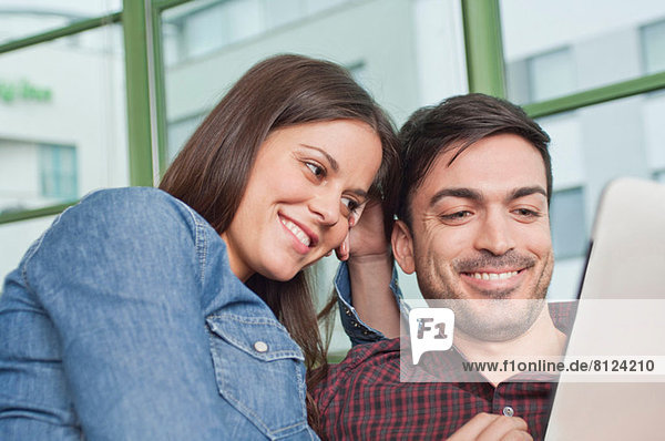 Glückliches junges Paar beim Betrachten des digitalen Tabletts