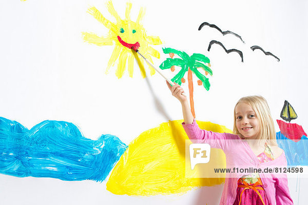Junges Mädchen malt lächelndes Sonnengesicht an der Wand