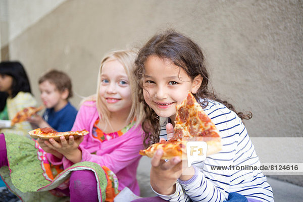 Kleine Gruppe von Kindern beim Pizzaessen im Freien