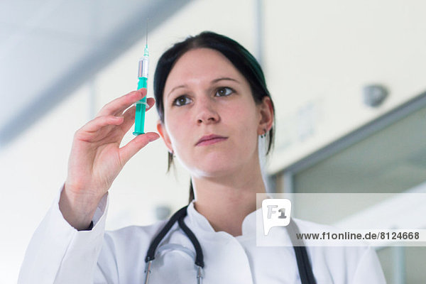 Portrait of female doctor holding up syringe