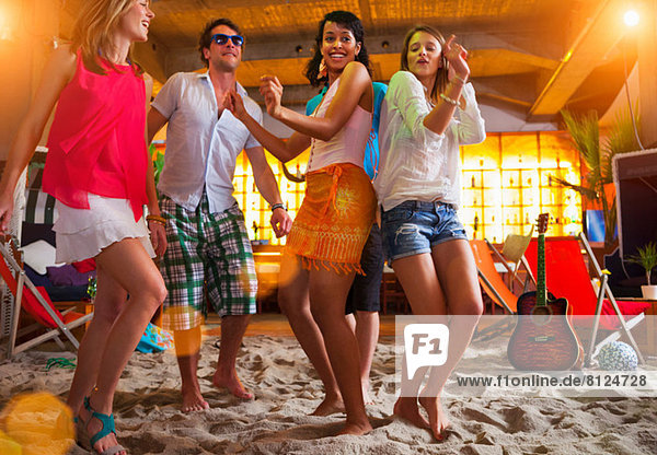 Friends dancing on sand at indoor beach bar