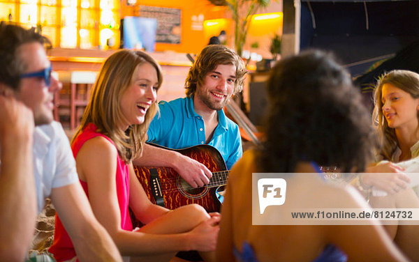 Freunde genießen das Gitarrenspiel in der Bar